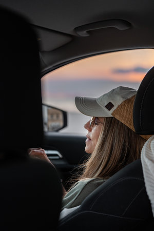 Woman relaxing in the car enjoying sunset view on road trip