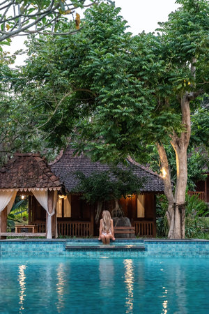 Tourist woman relaxing by the pool of a luxurious tropical resort in baliの写真素材