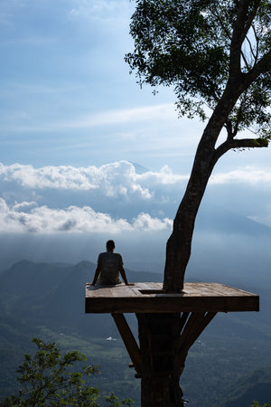 Tourist relaxing on wooden platform enjoying scenic mountain view in baliの写真素材