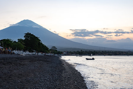 Fishing boats resting on shore at sunset with agung volcano in background