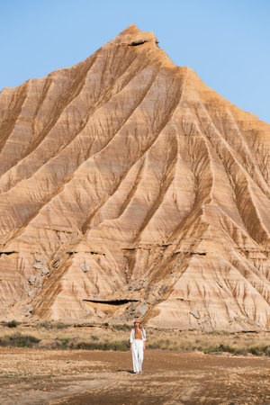 Woman walking in desert landscape with impressive eroded mountain in bardenas reales, navarra, spainの写真素材