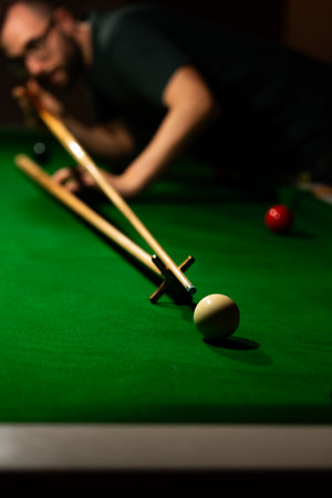Player aiming white ball on snooker table with rest
