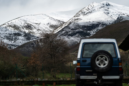 Off-road vehicle parked near snowy mountain range, embarking on winter adventureの写真素材