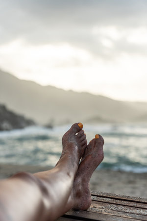 Legs of woman relaxing on the beach enjoying the sunset in tayrona park, colombiaの写真素材