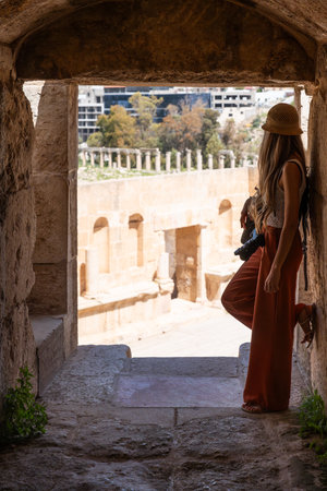 Rear view of blonde woman with hat looking the Ancient Jerash ruins, Jordanの写真素材