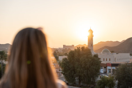 Defocused woman enjoying sunset view over oman cityscapeの写真素材