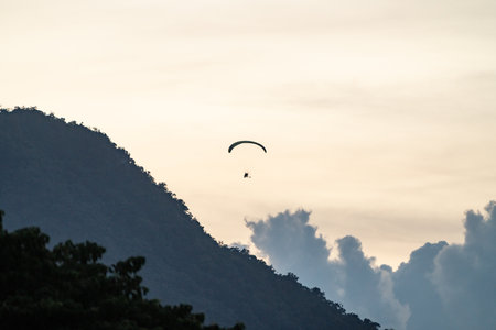 Paramotor flying over tropical mountain ridge at sunsetの写真素材