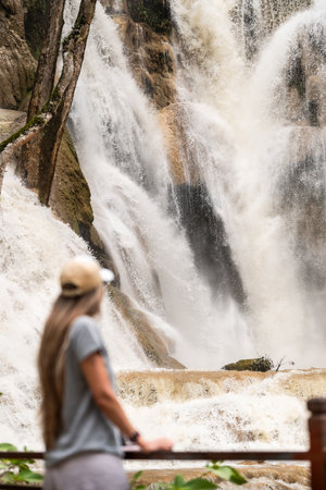 Woman admiring gushing Kuang si waterfall in natural jungle landscapeの写真素材