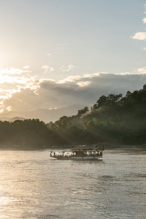 Boat cruising along river at golden hour sunsetの写真素材