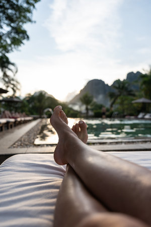 Legs relaxing by pool watching beautiful mountain sunsetの写真素材