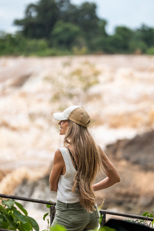 Woman exploring nature, enjoying powerful waterfall viewの写真素材