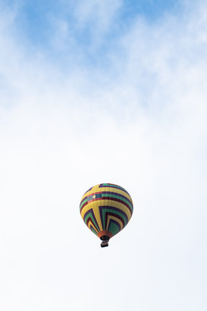Colorful hot air balloon floating across blue skyの写真素材