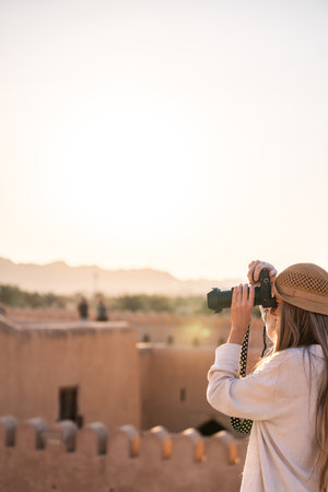 Woman photographer traveling oman capturing Nizwa fort view at sunsetの写真素材