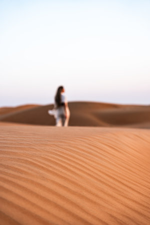 Defocused woman exploring desert dunes in oman with blurred backgroundの写真素材