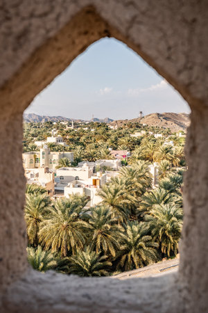 Arch framing traditional omani mountain village with date palm treesの写真素材