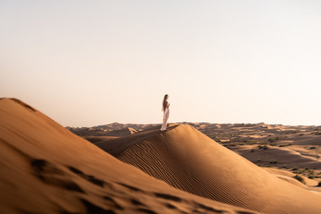 Woman standing on desert dune exploring oman landscape in sunsetの写真素材