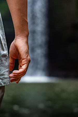 Tourist enjoying waterfall in tropical rainforest: hand close-upの写真素材