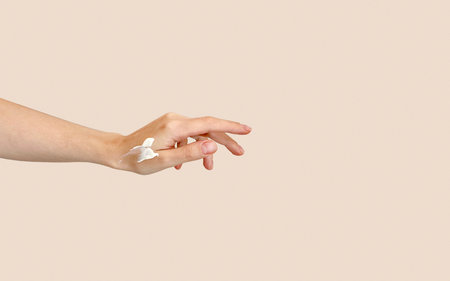 Female hand with cream on a beige background. Copy space.の写真素材