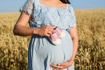 young pregnant woman in the field. beautiful pregnant woman in wreath relaxing in the summer nature meadowの写真素材