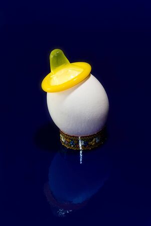 yellow condom on a white chicken eggの写真素材