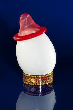 red condom on a white chicken egg, on a blue backgroundの写真素材