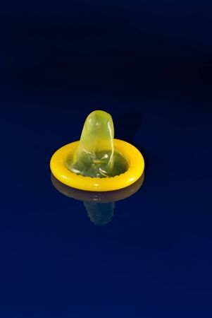 yellow condom on a blue background close upの写真素材