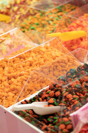 Colorful bright orange green jelly lollies (sweets) in transparent boxes and scoop on showcase in...
