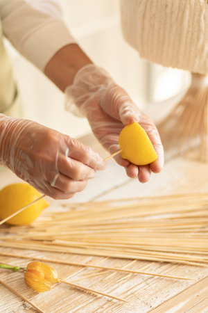 Hobby and activity:florist makes edible fruits arrangement gift on wooden table:strings lemon on skewers.How to make handmade edible bouquet: steps, tutorial.Healthy deliciousの写真素材
