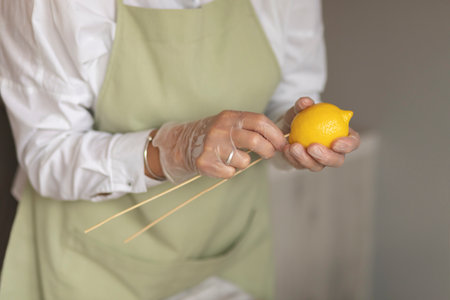 Hobby and activity:florist makes edible fruits arrangement gift on wooden table: chops lemon on skewers.How to make handmade edible bouquet: steps, tutorial.Healthy deliciousの写真素材