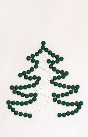 White background, mockup for medicine, Christmas tree made of green white pills, tablets,vitamins spirulina. Merry Christmas, Happy New Year concept, pharmacy postcard,flatly, top view, copy spaceの写真素材