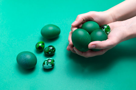Womans hands holding blue green Easter chicken quail eggs on blue background. Pascha or Resurrection Sunday, Christian festival and cultural holiday concept. Monochromatic. Closeup,Horizontal planeの写真素材