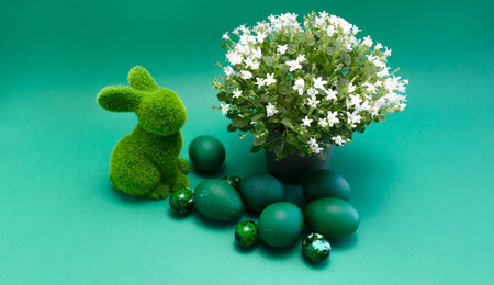 Happy Easter green bunny, rabbit with blue colored chicken quail eggs on blue background. White spring flowers in pot. Pascha or Resurrection Sunday, Christian festival,cultural monochrome holiday.の写真素材