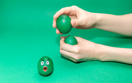 Celebrating Easter, Playing Easter Game With Egg. Green colored emotional hen egg with funny face,...