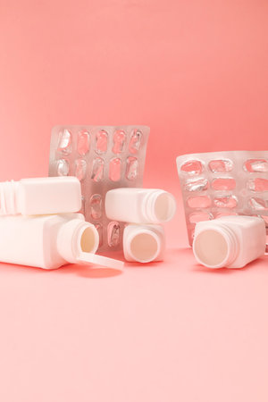 Empty plate with pills, capsule, vitamin bottles, containers on pink background. Medical,...