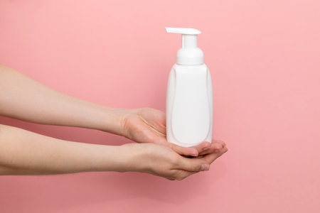 Female Hands Holding Blank White Dispenser Bottle, Plastic Tube On Pink Background. Hygiene, Cosmetic Beauty Product, Washing, Cleansing Intimate Gel, Foam. Daily Body Care. Horizontal Plane, Closeupの写真素材