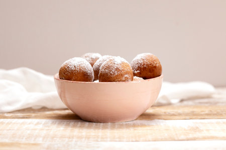 Paczki Or Zeppole In Pink Bowl With Powdered Sugar On Wooden Table. Fat Thursday Carnival or Tlusty Czwartek, Christian tradition Of Eating Doughnut, Delicious Donuts. Horizontal Plane.の写真素材