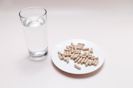 Top View Handful Of Pills, Capsules OF Slippery Elm And Glass Of Water on Table. Dietary Nutritional Supplement, Medication. Ulmus Fulva, Herbal Remedy Concept. Horizontal Planeの写真素材