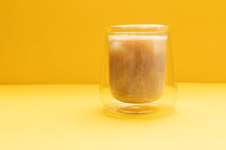 Closeup Drinking Glass With Pilk, Trendy Dirty Soda Drink. Combination Of Soda, Dairy Beverages, Ice Cubes on Yellow Background. Refreshment. Horizontal Plane, Copy Space For Textの写真素材