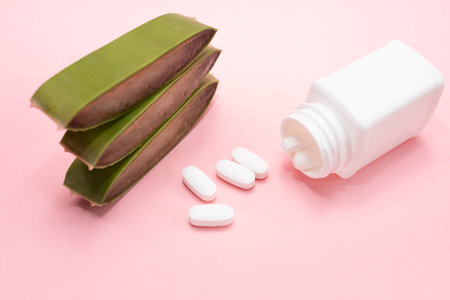 Green Fresh Juicy Aloe Vera Slice With Medicine Herbal Capsule Pills In White Plastic Bottle On Pink Background. Pharmacy, Cosmetics, Natural Medicine, Product. Horizontal Plane, Closeupの写真素材