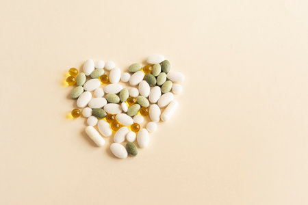 Flat lay Colorful Pile of Scattered Capsules, Pills, Vitamins in Heart Shape on Beige Background. Medical Supplements, Tablets or Drug Pharmaceutical Concept. Flatly. Health Insurance, Horizontal.の写真素材