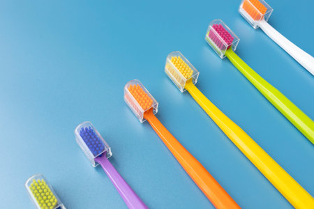 Top View Many Colorful Antibacterial Toothbrushes on Blue Background. Flat Lay Set for Dental Hygiene, Bathing Self Care Products. Horizontal Planeの写真素材