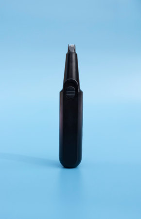 Electric Nose or Ear, Eyebrow, Facial Hair Trimmer On Blue Background. Removal Unwanted Hair Device. Personal Hygiene. Shaver, Epilator. Home Haircut Kit. Vertical Planeの写真素材