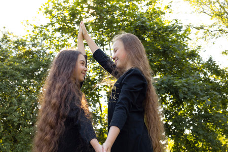Siblings Day Two Children, Sisters Smile Holding Hands and Looking At Each Other, Green Trees, Park...