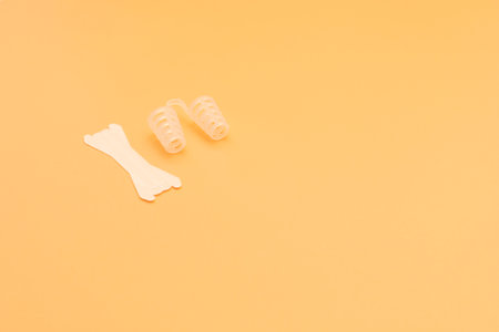 Mockup Anti Snoring Device. Nose Relief Nasal Dilator and White Nasal Strip on Peach Yellow Background, Sleeping Apnea Solution for Nasal Breathers, Snoring Problem. Space For Text Horizontal Plane.の写真素材