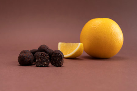Vegan Raw Sweet Balls made of Organic Cocoa beans With Dry Citrus Fruits on Brown Background. Orange is beside. Horizontal Plane. Healthy Food, Dessertの写真素材