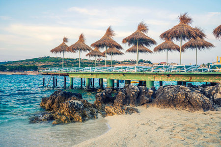 empty chairs under thatched umbrellas on the beach in albaniaの写真素材