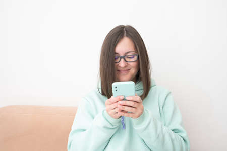 Portrait of a smiling casual woman holding smartphone over white background