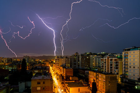 Lightning storm over city in purple lightの写真素材