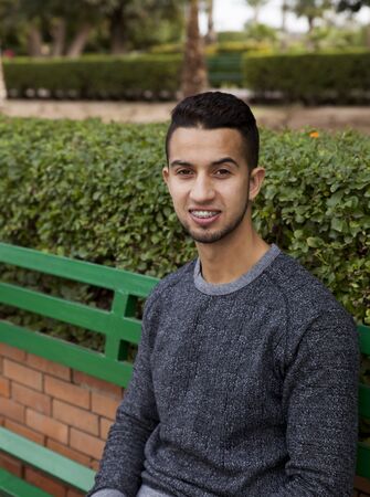 Portrait of a young arab man sitting outdoors and smiling
