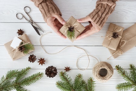 Preparation christmas gifts on a white wooden table with fir branches